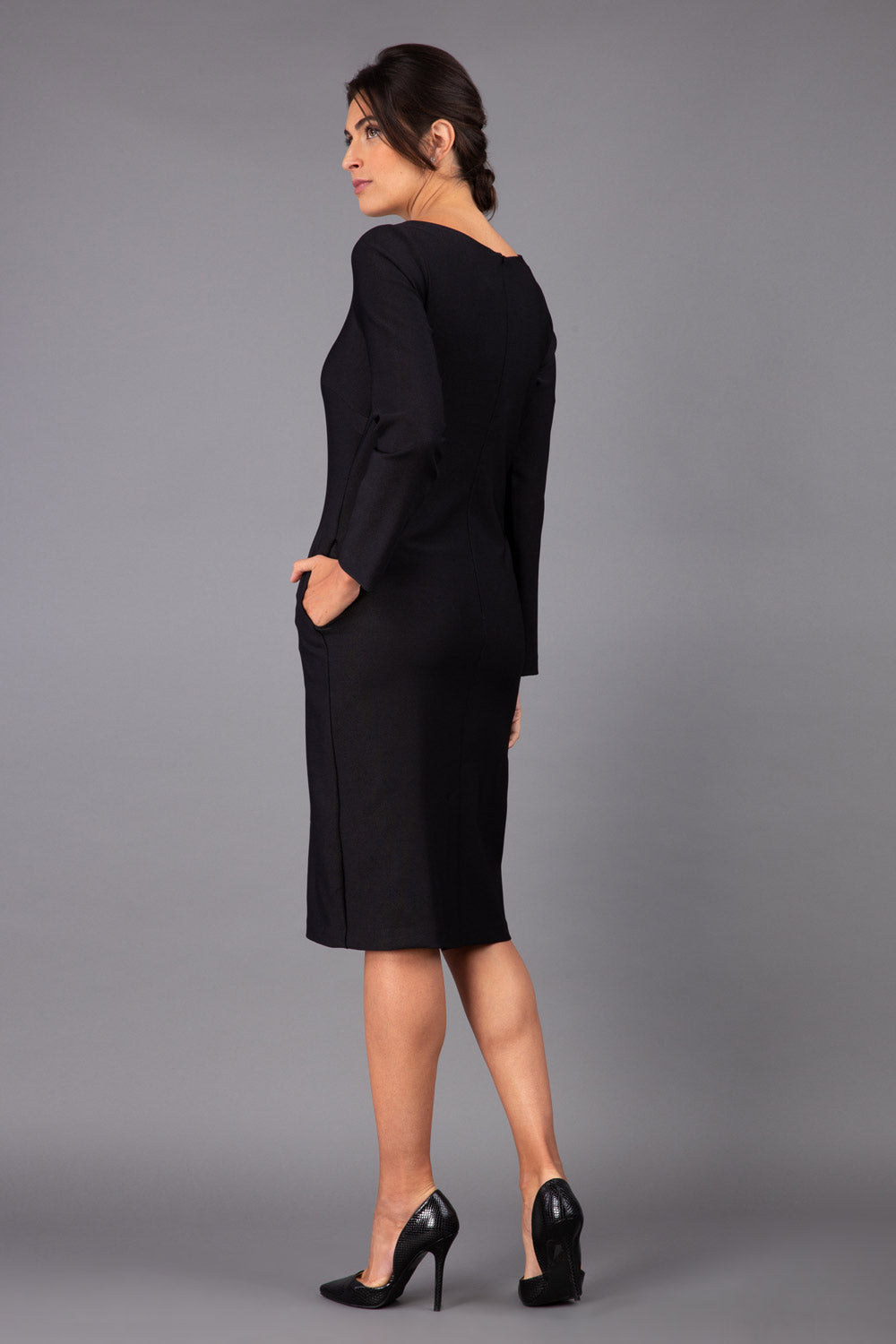 brunette model wearing diva catwalk cora white pencil dress with long sleeves and rounded neckline with pockets in colour black on side front