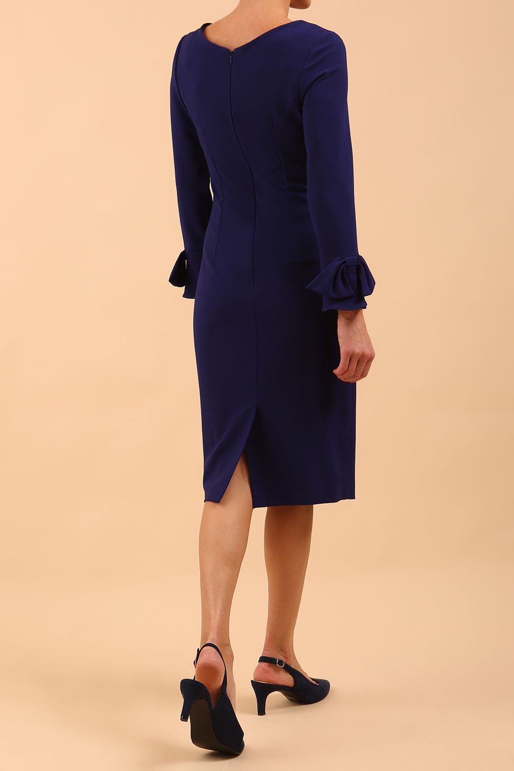 brunette model wearing diva catwalk fitted dress with sleeves called Alma Pencil-skirt dress in colour oxford blue with bow detail on sleeves front