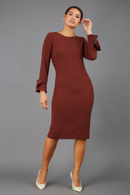 brunette model wearing diva catwalk fitted dress with sleeves called Alma Pencil-skirt dress in colour mahogany brown with bow detail on sleeves front
