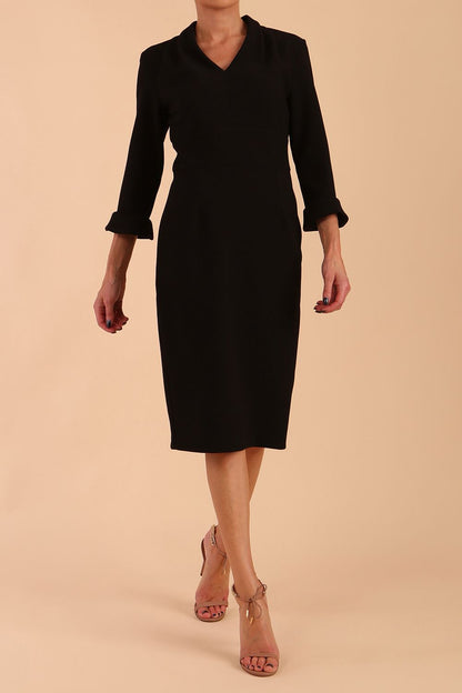 brunette model wearing diva catwalk adriana pencil dress with low v-neck and pleating around shoulders with three quarter sleeve detailed on end and wide waistband in black front
