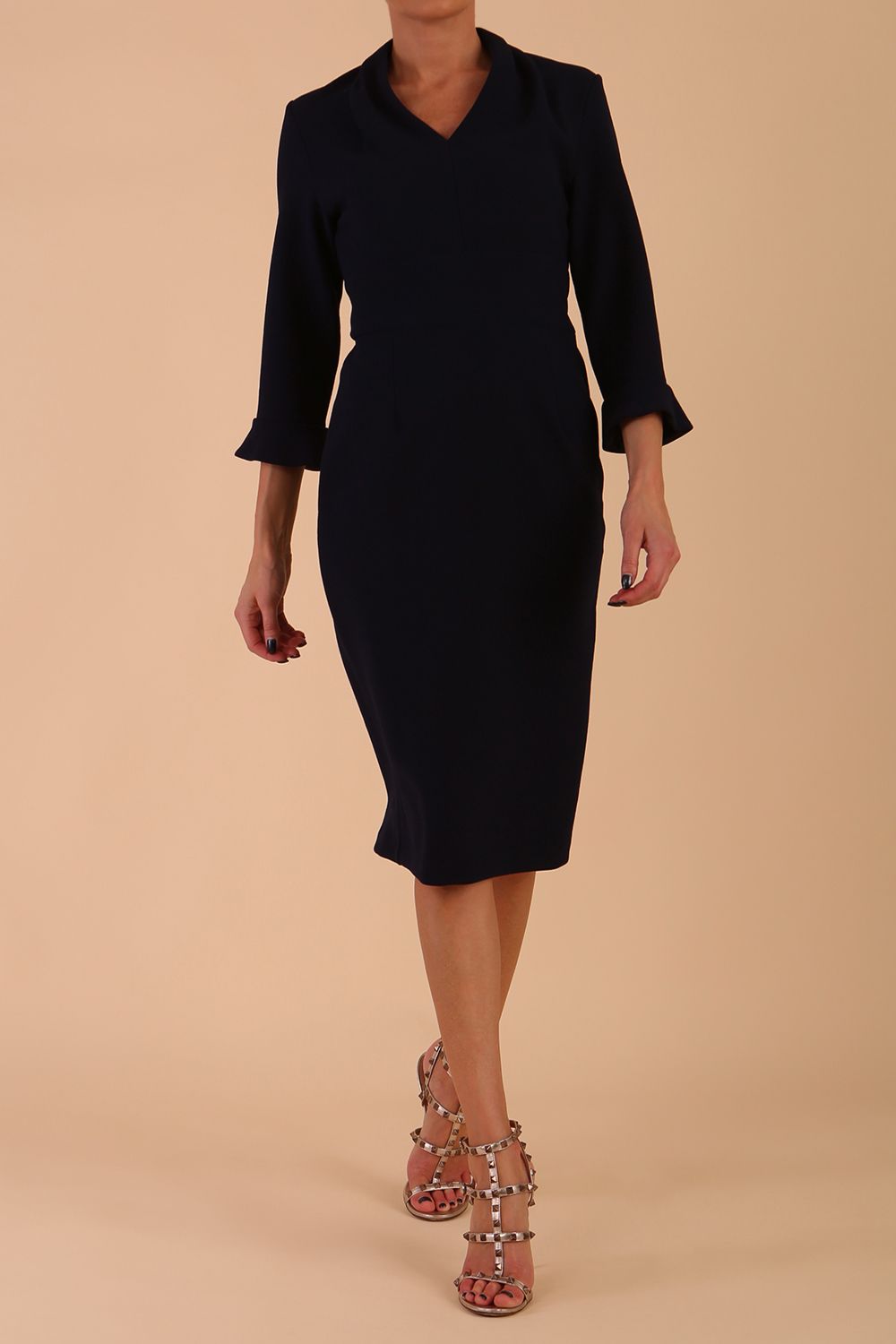 brunette model wearing diva catwalk adriana pencil dress with low v-neck and pleating around shoulders with three quarter sleeve detailed on end and wide waistband in dark navy front