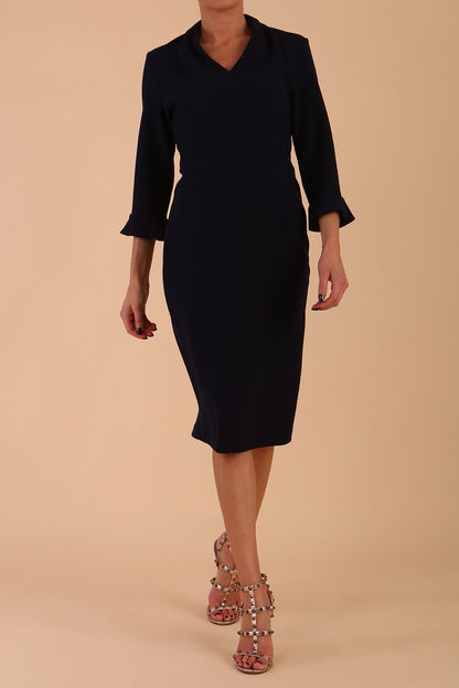 brunette model wearing diva catwalk adriana pencil dress with low v-neck and pleating around shoulders with three quarter sleeve detailed on end and wide waistband in dark navy front