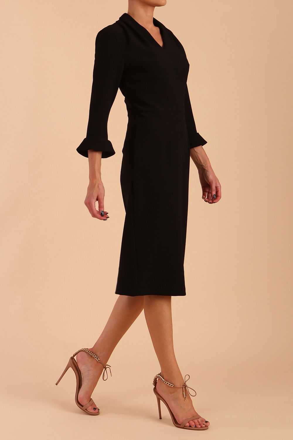 brunette model wearing diva catwalk adriana pencil dress with low v-neck and pleating around shoulders with three quarter sleeve detailed on end and wide waistband in black front