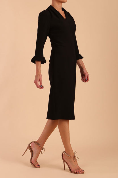 brunette model wearing diva catwalk adriana pencil dress with low v-neck and pleating around shoulders with three quarter sleeve detailed on end and wide waistband in black front