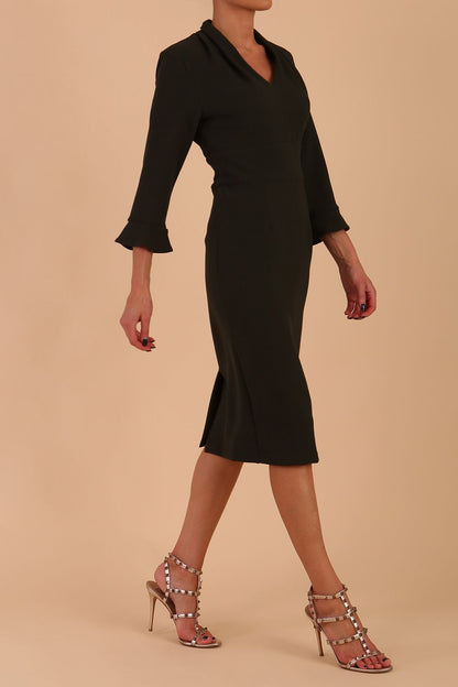 brunette model wearing diva catwalk adriana pencil dress with low v-neck and pleating around shoulders with three quarter sleeve detailed on end and wide waistband in obsidian green front side