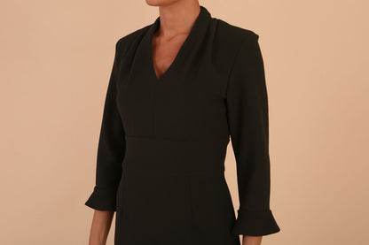 brunette model wearing diva catwalk adriana pencil dress with low v-neck and pleating around shoulders with three quarter sleeve detailed on end and wide waistband in obsidian green front side