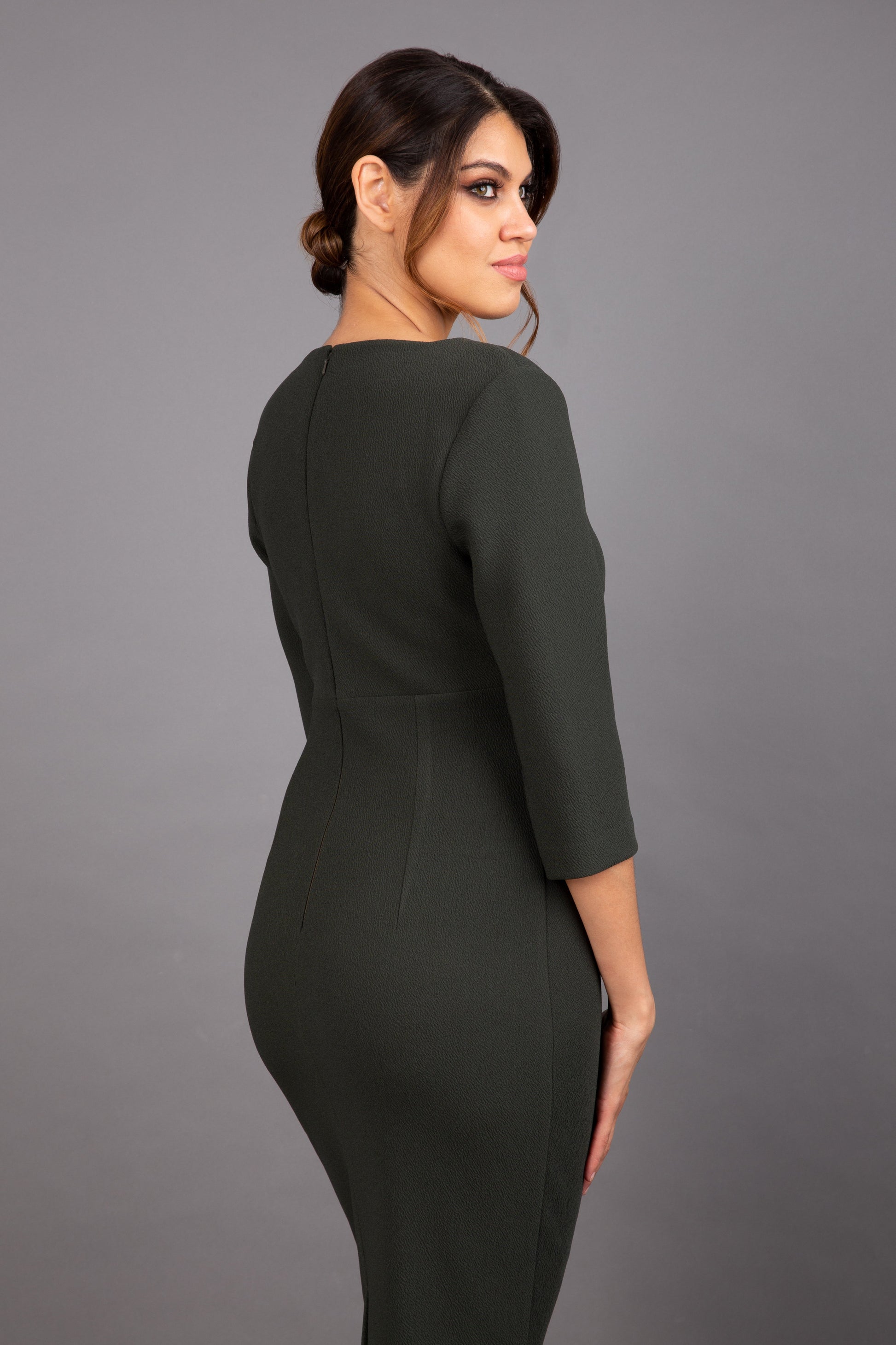 Brunette model wearing Diva Catwalk Lovell Pencil Dress in Obsidian Green with lowered sweetheart neckline and three quarter sleeve with gathering at the bust front