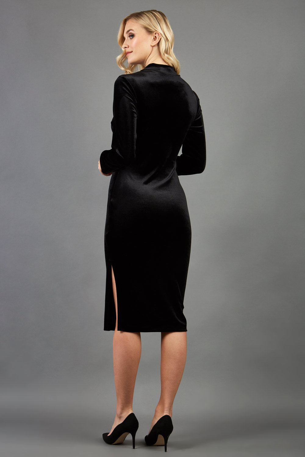 brunette model wearing diva catwalk clipper pencil skirt dress velvet sleeved style with a keyhole detail and high neck and split on a side of the skirt in colour black front