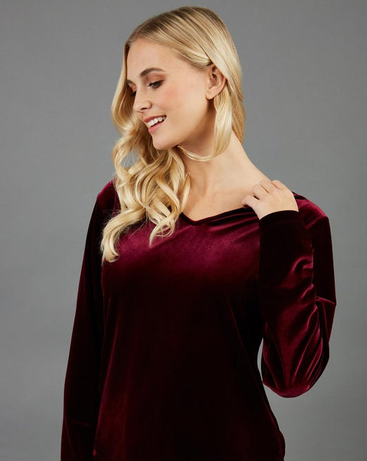 blonde model wearing diva catwalk dahlia asymmetric velvet top with sleeves in burgundy front