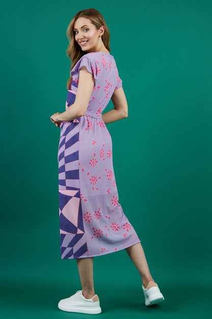 model is wearing diva catwalk midi length printed dress with short sleeves and belt detail in purple front