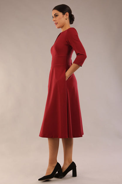 Brunette model is wearing diva catwalk casares swing dress with a keyhole neckline three quarter sleeve dress with pocket detail in Wine front side (Wine)