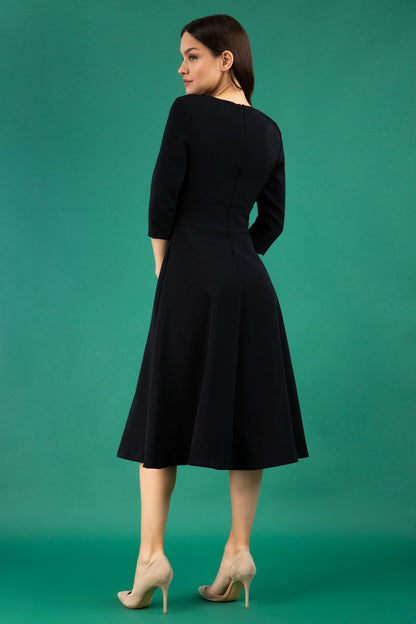 Brunette model is wearing diva catwalk casares swing dress with a keyhole neckline three quarter sleeve dress with pocket detail in black back (Black)