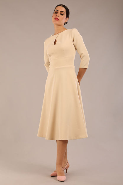Brunette model is wearing diva catwalk casares swing dress with a keyhole neckline three quarter sleeve dress with pocket detail in Sandshell Beige front (Sandshell Beige)