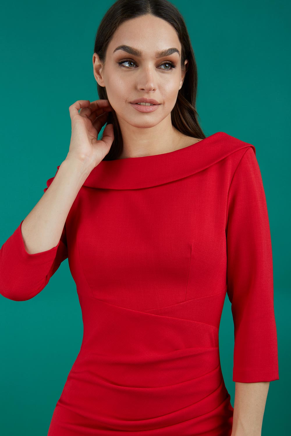 A brunette model is wearing a round neckline pencil dress with pleating on the tummy area in red front image