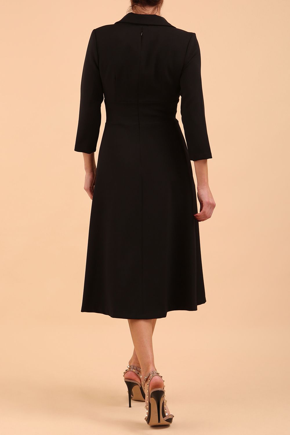 A blonde model is wearing a swing black three quarter sleeve dress with oversized collar and pockets in the skirt  