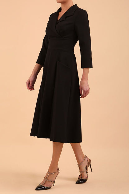 A blonde model is wearing a swing black three quarter sleeve dress with oversized collar and pockets in the skirt  