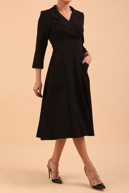 A blonde model is wearing a swing black three quarter sleeve dress with oversized collar and pockets in the skirt  