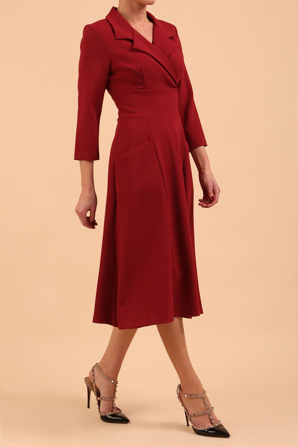 A blonde model is wearing a swing wine three quarter sleeve dress with oversized collar and pockets in the skirt  