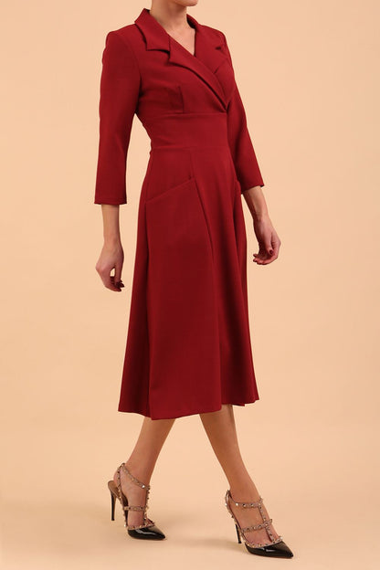 A blonde model is wearing a swing wine three quarter sleeve dress with oversized collar and pockets in the skirt  