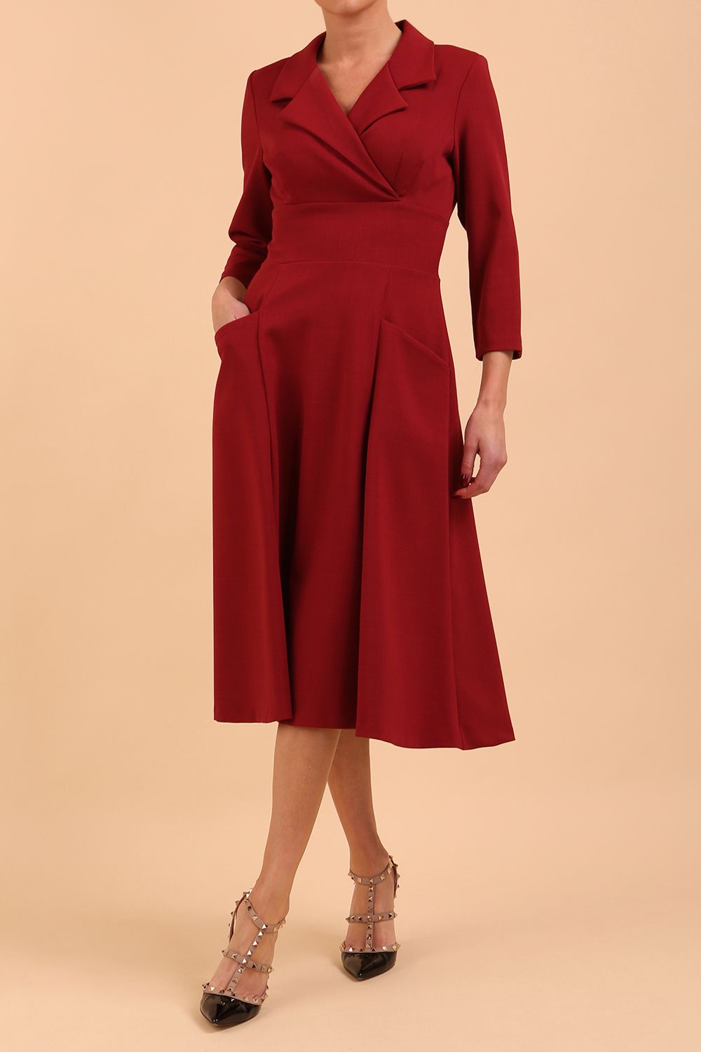 A blonde model is wearing a swing wine three quarter sleeve dress with oversized collar and pockets in the skirt  