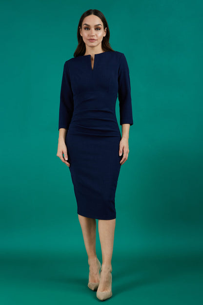 model is wearing diva catwalk chandos sheath dress with three quarter sleeve and slit in the middle of the neckline in navy blue front