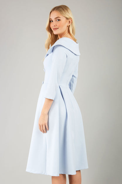 model is wearing diva catwalk gatsby swing dress with pocket detail and wide v-neck collar and buttons down the front panel in celestial blue front