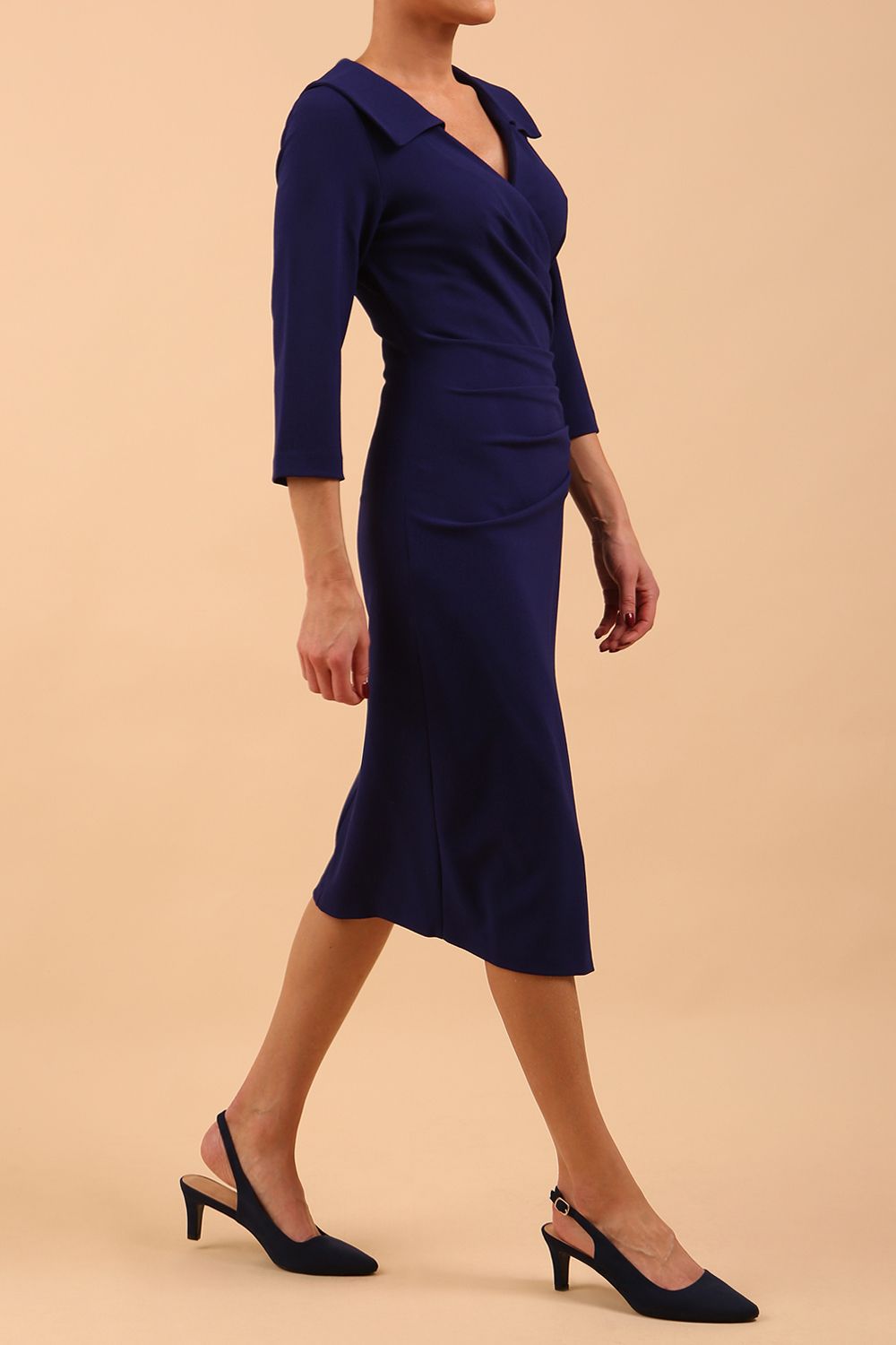  model is wearing diva catwalk liesel wrap pencil sleeved dress with collar half way around low v-neck in oxford blue front