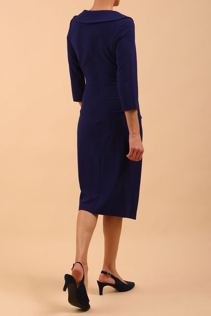  model is wearing diva catwalk liesel wrap pencil sleeved dress with collar half way around low v-neck in oxford blue front