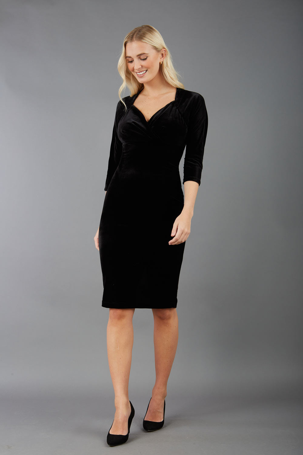 A blonde model is wearing a velvet pencil sweetheart neckline dress by diva catwalk in black back image