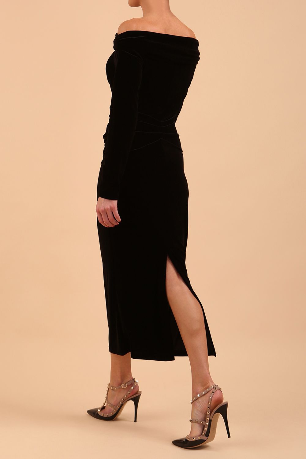 A blonde Model is wearing an off shoulder bardot neckline velvet stretch midi dress in red by diva catwalk back image