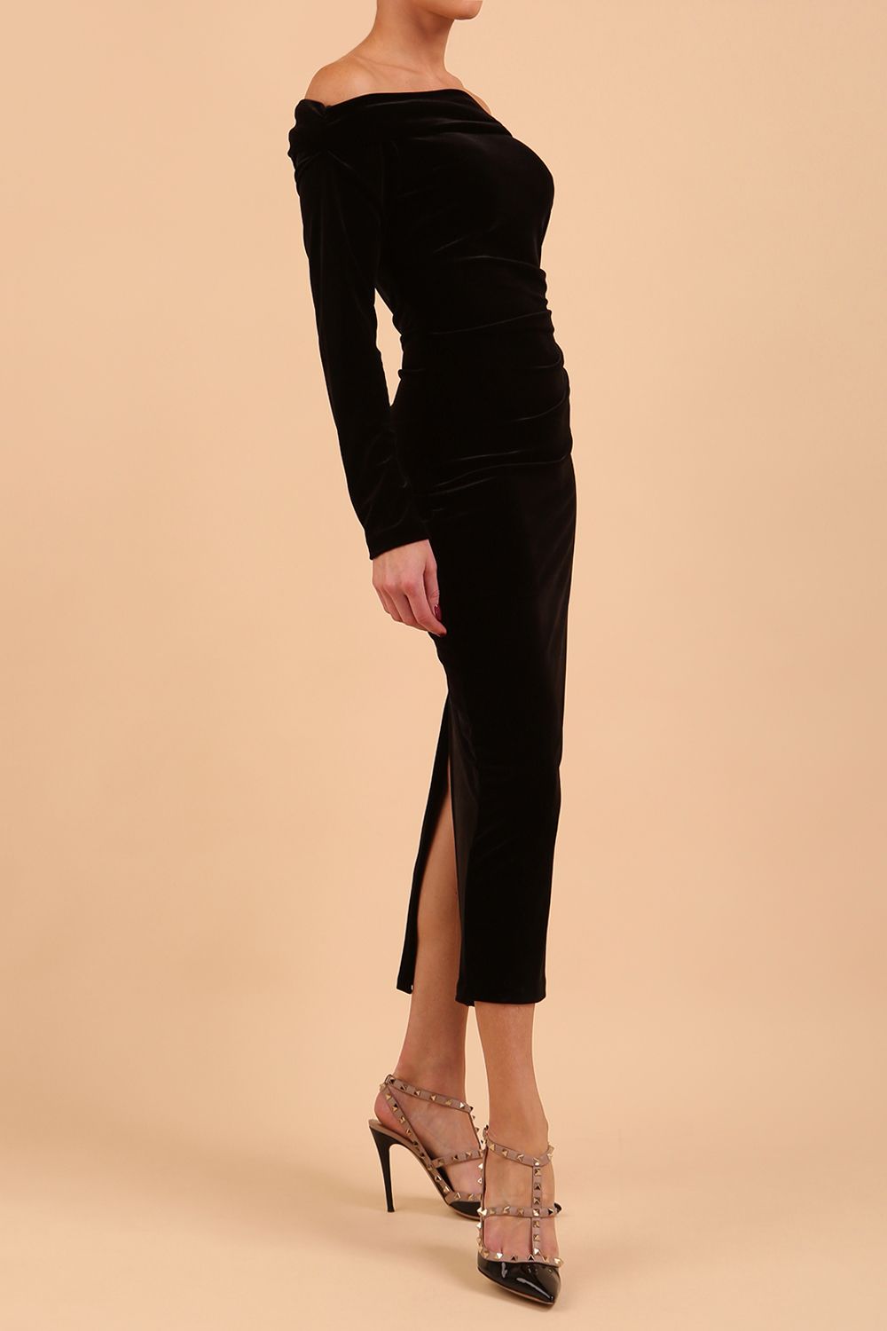 A blonde Model is wearing an off shoulder bardot neckline velvet stretch midi dress in red by diva catwalk back image
