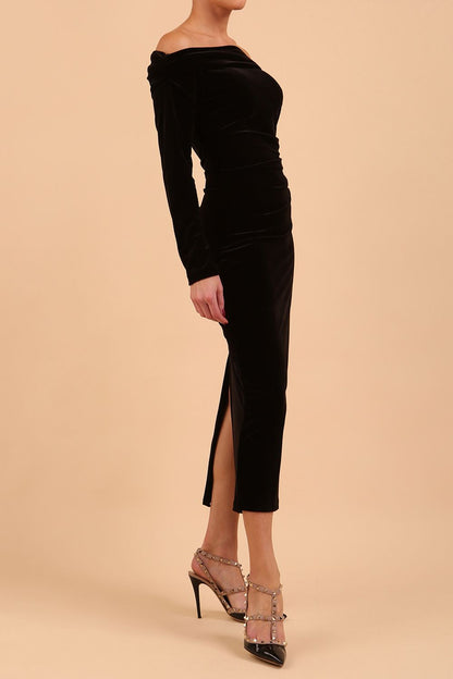 A blonde Model is wearing an off shoulder bardot neckline velvet stretch midi dress in red by diva catwalk back image