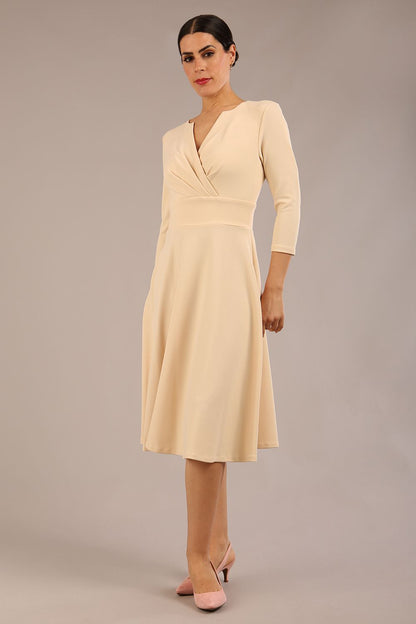 brunette model is wearing a diva catwalk january sleeved a-line swing v-neck dress in marvel fabric in beige colour front 