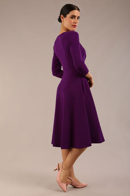 brunette model is wearing a diva catwalk january sleeved a-line swing v-neck dress in marvel fabric in deep purple colour front side
