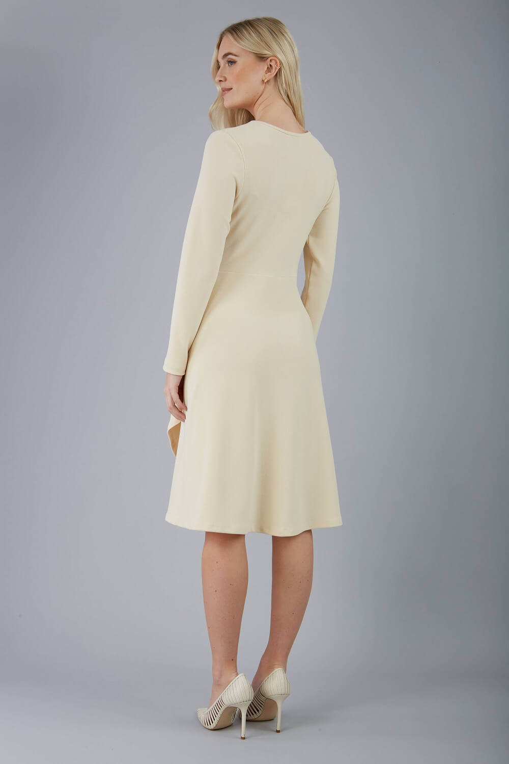 blonde model is wearing diva catwalk moraig swing long sleeve dress with high cowl neckline and wrap skirt in beige front