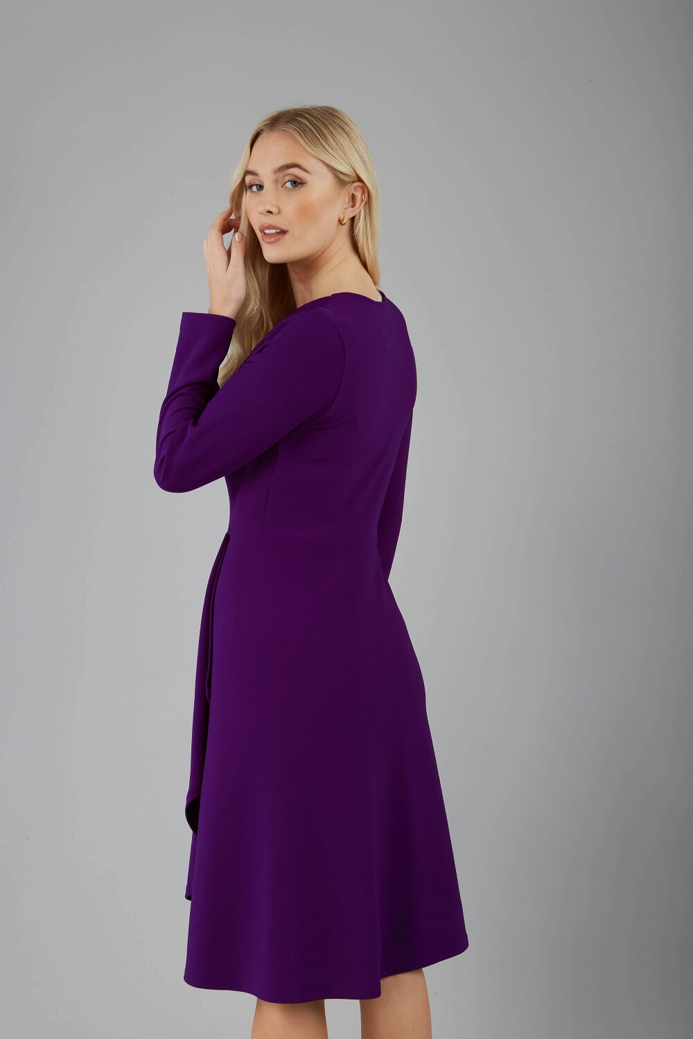 blonde model is wearing diva catwalk moraig swing long sleeve dress with high cowl neckline and wrap skirt in deep purple front