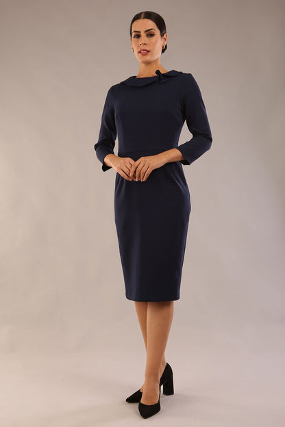 brunette model is wearing a diva catwalk  Helium 3/4 Sleeved Pencil Dress with 3/4 sleeve and knee length and bow detail on the neckline in navy blue colour front 