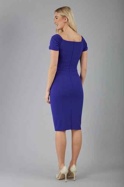 blonde model is wearing diva catwalk laurentia pencil odd shoulder dress with bardot neckline with gathering on shoulders in spectrum indigo colour front
