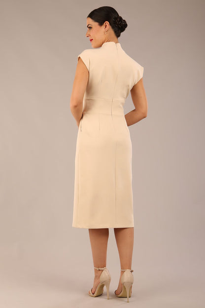 brunette Model is wearing a diva catwalk Derby pencil skirt dress cap sleeves with buttons details at the waistband and star neckline below the knee length with pockets in sandshell beige colour front image 