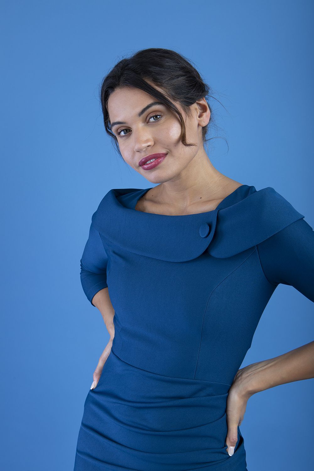 brunette model is wearing diva catwalk pencil dress with collar and a button detail on a side with 3/4 sleeve in glorious teal front