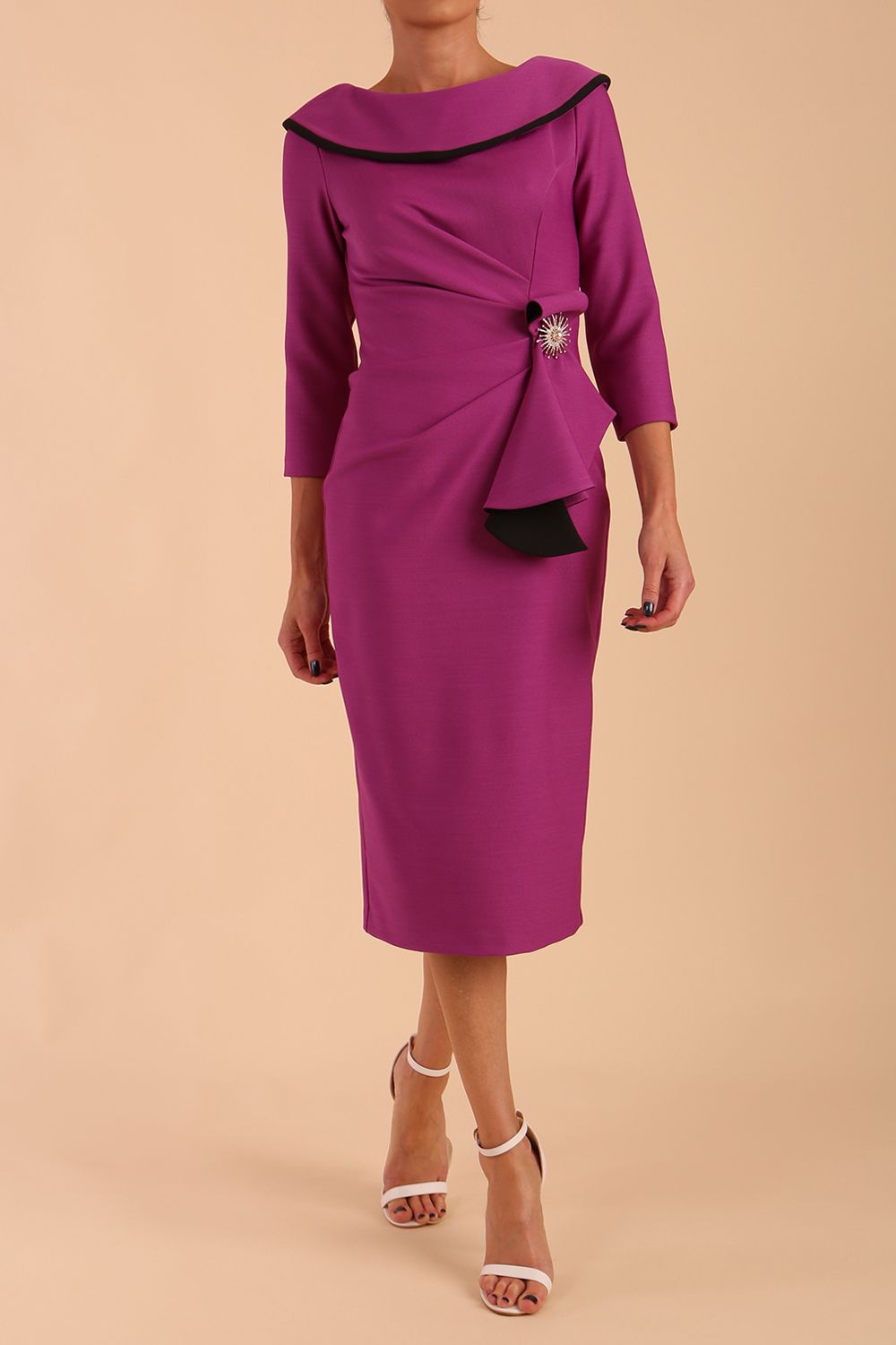 odel wearing diva catwalk Seed Elsye 3/4 Sleeve Knee Length Pencil Dress with Fold over bateau collar neckline with contrast piping and Bow feature on the left side of the bodice with decorative brooch in Dawn Purple colour front