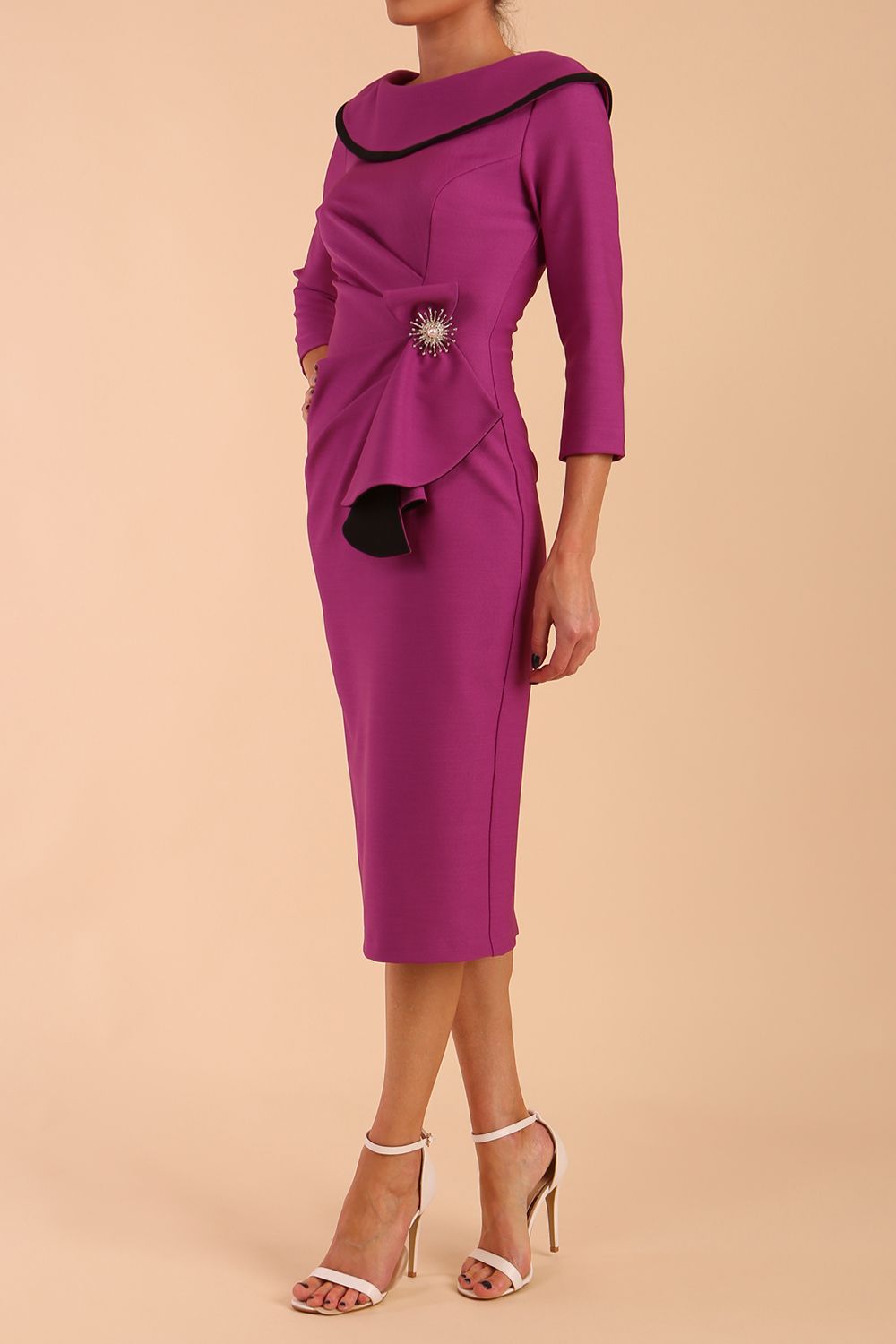 odel wearing diva catwalk Seed Elsye 3/4 Sleeve Knee Length Pencil Dress with Fold over bateau collar neckline with contrast piping and Bow feature on the left side of the bodice with decorative brooch in Dawn Purple colour front