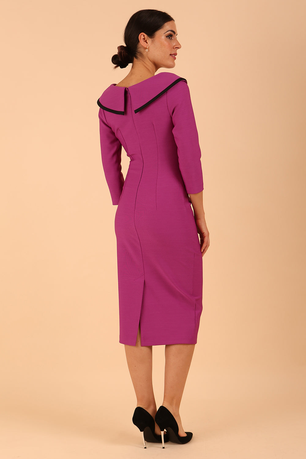 odel wearing diva catwalk Seed Elsye 3/4 Sleeve Knee Length Pencil Dress with Fold over bateau collar neckline with contrast piping and Bow feature on the left side of the bodice with decorative brooch in Dawn Purple colour front