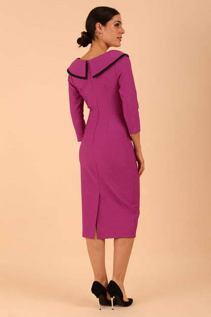 odel wearing diva catwalk Seed Elsye 3/4 Sleeve Knee Length Pencil Dress with Fold over bateau collar neckline with contrast piping and Bow feature on the left side of the bodice with decorative brooch in Dawn Purple colour front