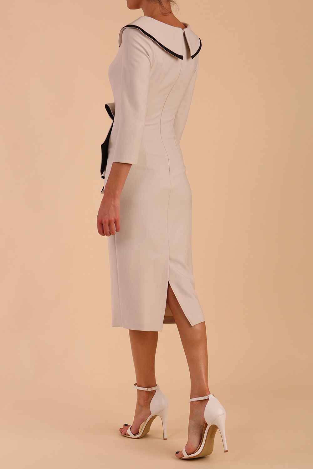 Model wearing diva catwalk Seed Elsye 3/4 Sleeve Knee Length Pencil Dress with Fold over bateau collar neckline with contrast piping and Bow feature on the left side of the bodice in Sandy Cream colour front side (Sandy Cream / Black Contrast)