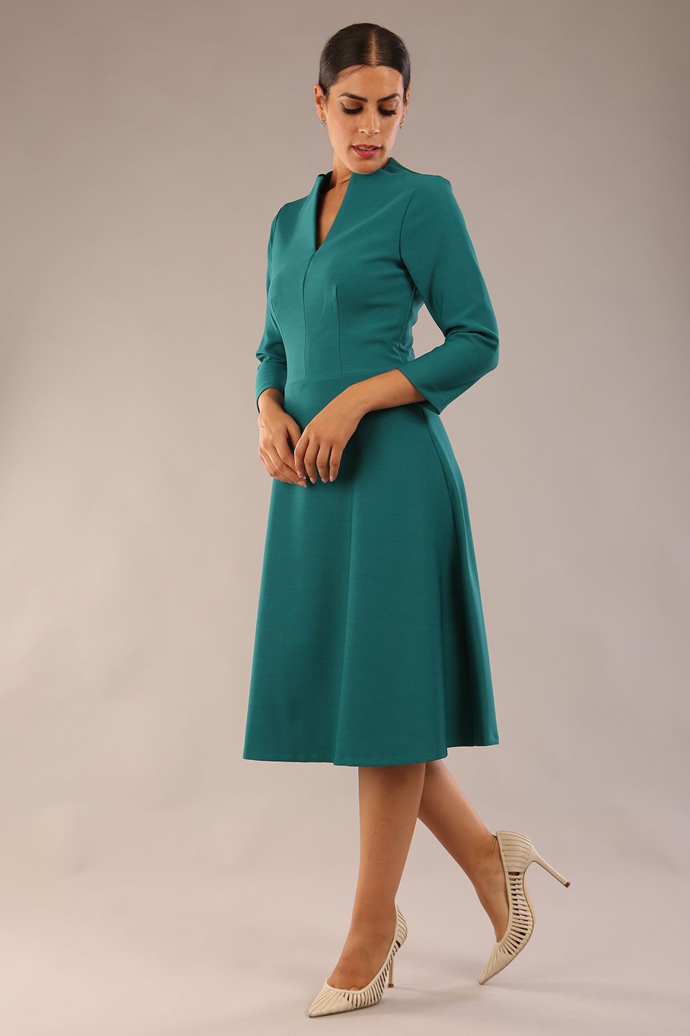 model is wearing diva catwalk palmerston vintage style a-line dress with sleeves and high neck with a slit in pacific green colour front