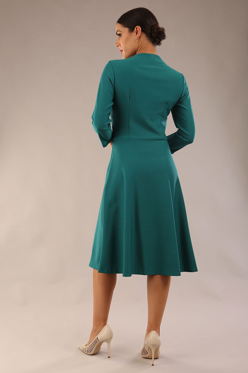 model is wearing diva catwalk palmerston vintage style a-line dress with sleeves and high neck with a slit in pacific green colour front