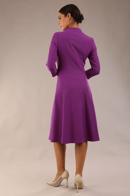 model is wearing diva catwalk palmerston vintage style a-line dress with sleeves and high neck with a slit in amethyst purple colour front