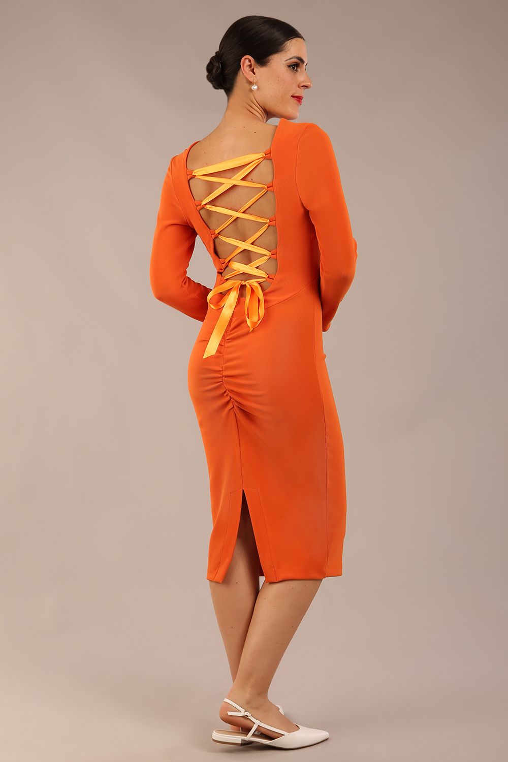 brunette model wearing a diva catwalk Zoey Sleeved Pencil Dress ribbon back with long sleeves and rushed details front and back in Amber Orange colour back