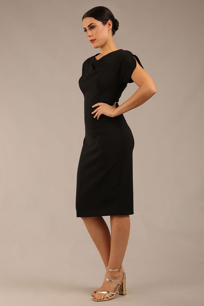 brunette Model wearing a diva catwalk Sheena Short Sleeve with an open split Knee Length Pencil Dress with Diamond Neckline in Black colour back